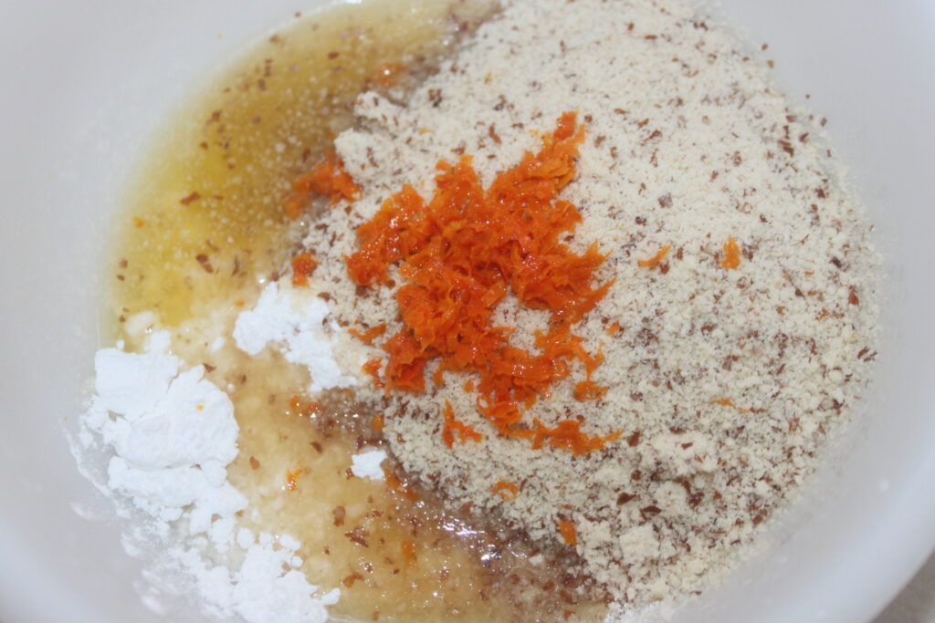 La farine, le zeste d'orange et plus encore sont mélangés dans un bol à mélanger pour la recette des Tartelettes à la crème d'orange, offrant une délicieuse touche de crème d'orange.
