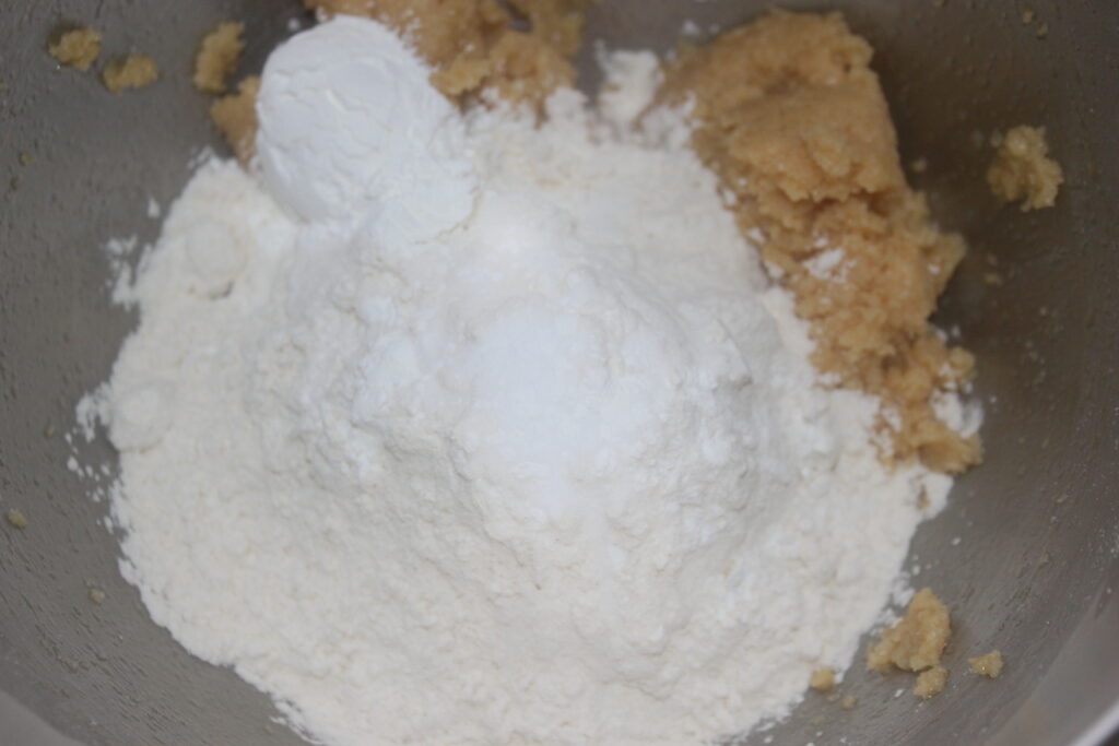 Un bol à mélanger contenant de la farine, du sucre et un agent levant combinés avec du beurre crémeux et du sucre crée la base parfaite pour des biscuits parsemés de mini M&M's colorés.