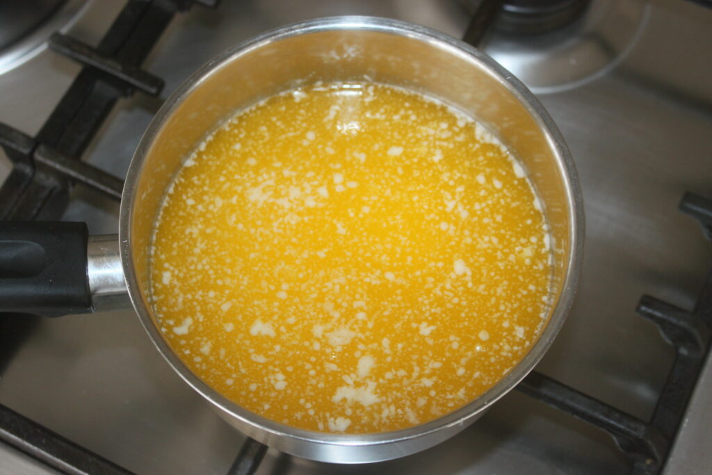 Une petite casserole sur une cuisinière contient du beurre fondant, prêt à infuser les saveurs d'un lot de baklava délicat.