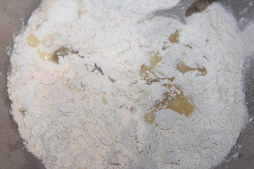 Un mélange de farine blanche et de petites quantités d'eau dans un bol, semblant partiellement combiné, attend l'ajout d'éléments salés comme du tofu ou des shitakés pour créer un plat délicieux.
